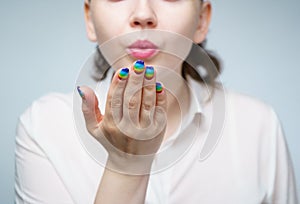 Image of woman with rainbow manicure doing air kiss