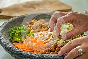 Image of a womans hands, preparing a salad.