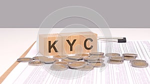 text KYC on wooden cubes on a wooden table with coins. this concept emphasizes the importance of Know Your Client photo