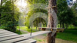 Image of wooden bridge and ropes hanging between trees in park. Extreme adventure park for children and adults