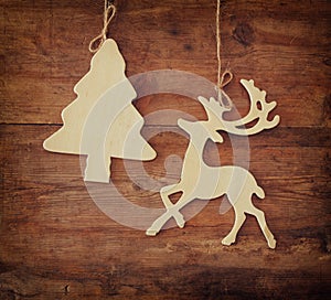 Image of wooden decorative christmas tree and reindeer hanging on a rope over wooden background.