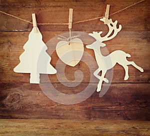 Image of wooden decorative christmas tree and reindeer hanging on a rope over wooden background.
