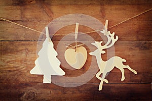 Image of wooden decorative christmas tree and reindeer hanging on a rope over wooden background