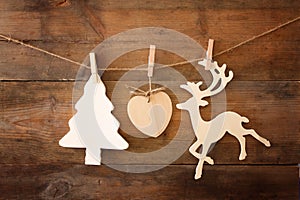 Image of wooden decorative christmas tree and reindeer hanging on a rope over wooden background