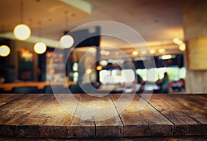 Image of wooden table in front of abstract blurred background of restaurant lights