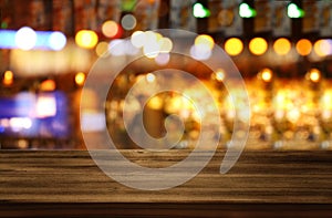 Image of wooden table in front of abstract blurred restaurant lights background