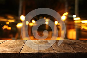 Image of wooden table in front of abstract blurred restaurant lights background