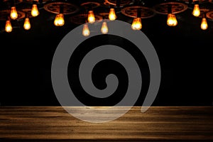 Image of wooden table in front of abstract blurred restaurant lights background.