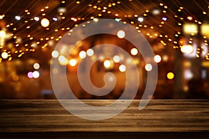 Image of wooden table in front of abstract blurred restaurant lights background