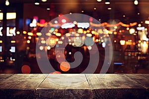 Image of wooden table in front of abstract blurred restaurant lights background