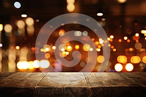 Image of wooden table in front of abstract blurred restaurant lights background