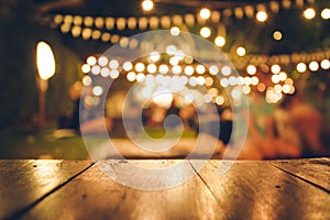 Image of wooden table in front of abstract blurred restaurant lights background