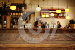 Image of wooden table in front of abstract blurred restaurant lights background