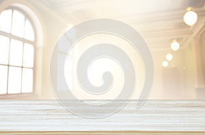 Image of wooden table in front of abstract blurred window light background