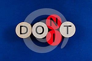 Image of word Don`t spelled on wooden pegs with second to the last circle replacing to spell the word Do It