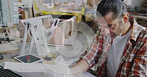 Image of world map and data processing over caucasian male carpenter working in workshop