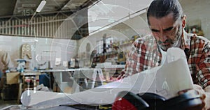 Image of world map and data processing over caucasian male carpenter working in workshop