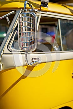 Image of a yellow tour bus with chrome rear view mirror