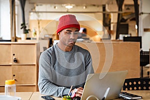 Image of young african american man using laptop while working in office