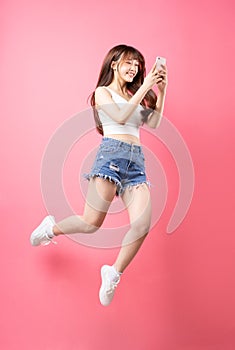 image of young asian girl jumping on pink background