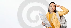 Image of young asian girl tourist, traveller with map and backpack posing against white studio background