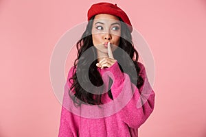 Image of young asian girl wearing beret holding index finger on lips