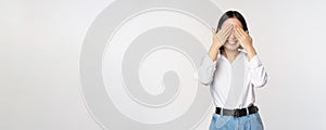 Image of young asian woman close her eyes and smiles, waits for surprise, anticipates, stands over white background