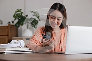 Image of young asian woman order online, shopping from home. Girl enter credit card info on webside to make purchase