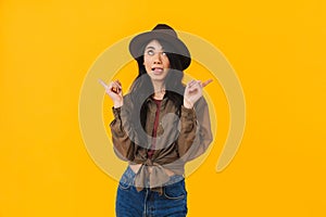 Image of young asian woman wearing hat smiling and pointing fingers