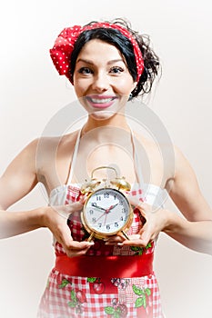 Image of young beautiful funny pinup young woman attractive girl with big smile holding alarm clock looking at camera