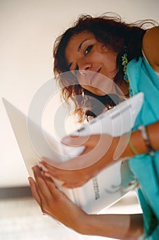 Image of young beautiful joyful woman smiling while working with laptop.