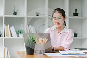 Image of young beautiful joyful woman smiling while working with laptop in office.