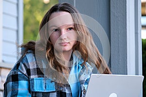 Image of a young beautiful joyful woman smiling while working with a laptop outdoors on the porch beautiful young teen