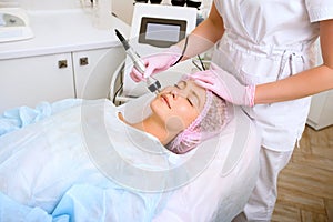 Image of a young beautiful woman dressed as a patient, lying on a couch in a cosmetology clinic.