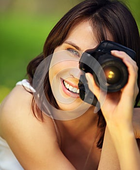 Image of young beautiful woman photographing in summer park