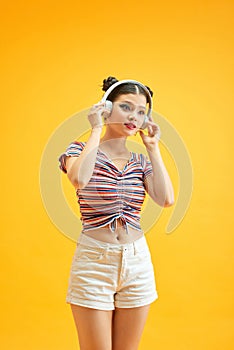 Image of young beautiful woman posing isolated over yellow background listening music with headphones