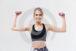 Image of young blond woman 20s dressed in sportswear working out and doing exercises with dumbbells during fitness in gym