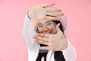 Image of young brunette asian woman smiling and gesturing photo frame