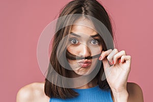 Image of young brunette woman having fun and putting her hair as mustache