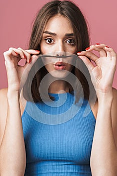 Image of young brunette woman having fun and putting her hair as mustache