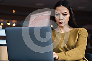 Image of young caucasian businesswoman working on laptop in office
