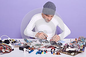 Image of young concentrated radioman working with faulty spare part of electronic device. Front view of young handsome computer