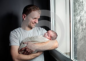 Image of young dad with cute little daughter in his arms. Father and newborn baby child indoor.