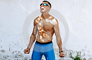 Image of young fit male athlete enjoying victory in the marathon outdoor. Handsome runner win the competition, screaming and