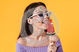 Image of young funny woman liking lollipop and smiling