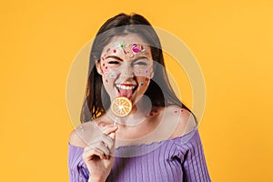 Image of young funny woman liking lollipop and smiling