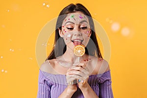 Image of young funny woman with stickers on face liking lollipop