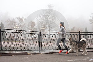 Image of young girl running with her dog, alaskan malamute