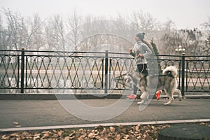 Image of young girl running with her dog, alaskan malamute