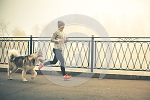 Image of young girl running with her dog, alaskan malamute